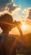 © sommersby - A person stands in silhouette against a stunning sunset, holding a camera up to capture the moment. The warm light of the setting sun illuminates the clouds and casts a golden glow over the landscape