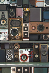 Wall of various old, colorful stereo speakers stacked on top of each other.