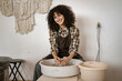 © sofiko14 - Young female potter sculpts ceramic dishes using a pottery wheel in a warm and inviting workspace.