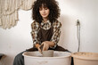© sofiko14 - Young female artist sculpting a ceramic bowl using a potter's wheel. Hands-on pottery creation in a studio setting.