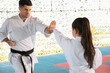 © New Africa - Girl practicing karate with coach on tatami outdoors
