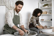 © sofiko14 - Man and woman potters at work, shaping clay on potter's wheels in pottery studio. Focus on craftsmanship and creativity.