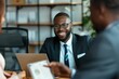 © Nognapas - Happy black financial advisor using touchpad with his clients during meeting in office.