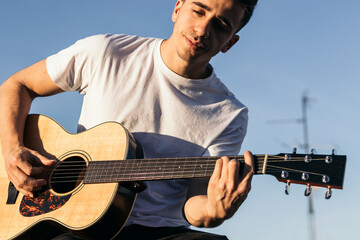 young man sitting playing acoustic guitar on a rooftop