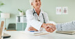 © HockleyMedia24/peopleimages.com - Happy woman, doctor and handshake with patient for consultation, agreement or checkup at hospital. Female person or medical professional shaking hands with client for meeting, deal or appointment