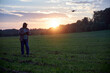 © Vieille Prune - a man launches a drone at sunset in a field