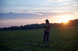 © Vieille Prune - a man launches a drone at sunset in a field