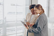 © Kostiantyn - Smiling female business people standing in modern coworking and using digital tablet together
