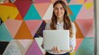© Alpa - Cheerful businesswoman standing while using laptop in office