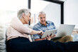© ReadyAtTheEase/peopleimages.com - Laptop, tablet and senior couple on sofa planning for retirement fund, savings and pension. Reading, relax and elderly man and woman with computer and digital technology for bills payment at home.