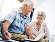 © ReadyAtTheEase/peopleimages.com - Writing, notebook and senior couple in home planning for retirement fund, savings and pension. Smile, investment and elderly man and woman with budget notes for bills, mortgage and debt payment.