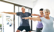 © ReadyAtTheEase/peopleimages.com - Yoga, senior people and teacher for help, stretching arms or wellness at home. Health care, elderly man or old woman with yogi instructor for exercise, balance or wellbeing with pilates class