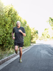 Road, running and senior man with energy for fitness, exercise and training outdoors with endurance for pace. Elderly athlete, male runner and action with movement, cardio goals and marathon