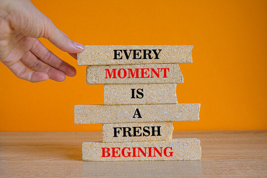 Every Moment is a Fresh Beginning quote on brick blocks. Beautiful wooden table orange background. Motivational concept.