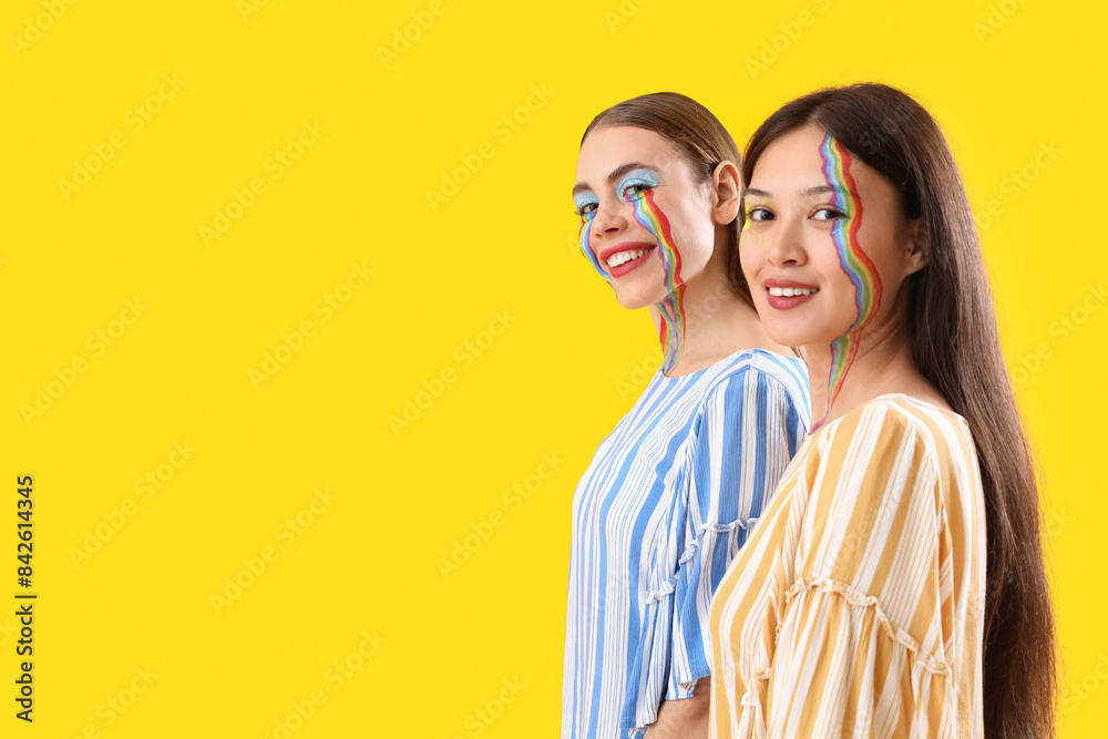 Young women with painted faces on yellow background