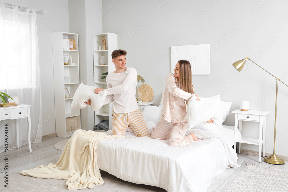 Happy young couple fighting pillows in bedroom