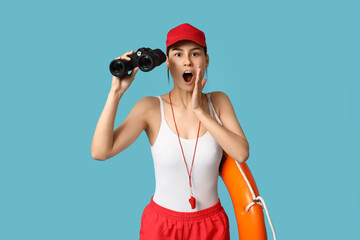 Canvas Print - Shocked female lifeguard with ring buoy and binoculars on blue background