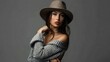 © adnan - Stylish woman modeling a chic off-shoulder knit sweater and wide-brim hat.