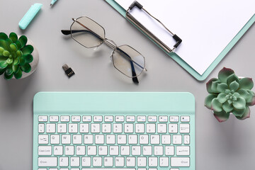 Wall Mural - Keyboard, eyeglasses and cactus on grey background. Top view