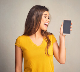 Poster - Screen, woman and display of phone in studio with mockup space for advertising, marketing or promotion. Surprise, technology and female person presenting cellphone isolated by gray background.