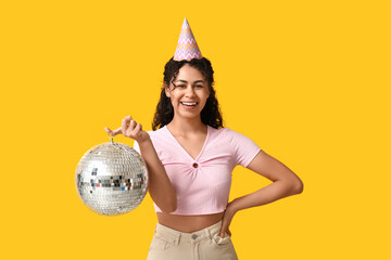 Poster - Beautiful young African-American woman in party hat with disco ball on yellow background