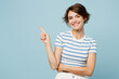 © ViDi Studio - Young smiling cheerful fun woman wears striped t-shirt casual clothes point index finger aside on area mock up isolated on plain pastel light blue cyan background studio portrait. Lifestyle concept.