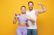 © ViDi Studio - Young strong fitness trainer instructor sporty two man woman wearing blue clothes spend time in home gym hold in hand protein energy bar isolated on plain yellow background. Workout sport fit concept.