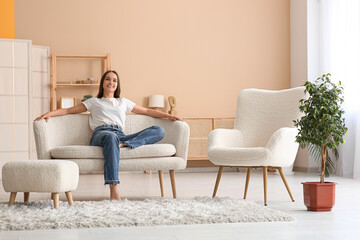 Wall Mural - Young pretty woman resting on sofa in living room