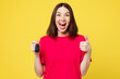 © ViDi Studio - Young surprised excited woman she wear pink t-shirt casual clothes hold in hand car key fob keyless system show thumb up isolated on plain yellow orange background studio portrait. Lifestyle concept.