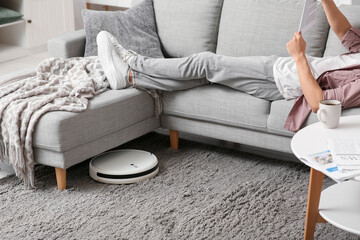 Sticker - Modern robot vacuum cleaner near sofa with resting man at home