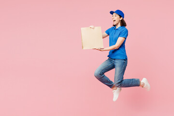 Sticker - Full body delivery girl employee woman wear blue cap t-shirt uniform workwear work as dealer courier hold brown clear blank craft paper bag jump high isolated on plain pink background Service concept