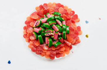 Watermelon-shaped jelly candies on hearts jelly sweets with sugar on a plate, top view.