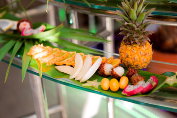 Wall Mural - A table with a variety of fruits and vegetables, including pineapple, apples, and oranges. The table is set up for a party or gathering