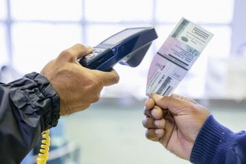 One person is showing a ticket to another person who is scanning it with a scanner