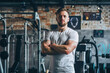 © GoodandEvil - Focused young man with arms crossed in a gym