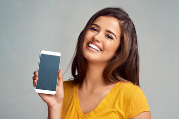 Poster - Portrait, woman and display of phone screen in studio with mockup space for advertising, marketing or promotion. Smile, technology and female person presenting cellphone isolated by gray background.