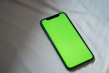 Smart phone with green screen on white fabric