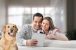 © BillionPhotos.com - Smiling young couple sitting on sofa with dog
