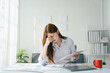 © PaeGAG - Student woman is sitting at a desk with a red mug and a stack of papers