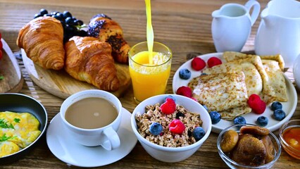 Wall Mural - Breakfast served with coffee, orange juice, scrambled eggs, cereals, pancakes and croissants.