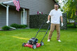 © F8  \ Suport Ukraine - Lawn care. Young man mows the grass with a lawn mower with a grass collector on a sunny summer day.
