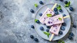 © lililia - Blueberry Popsicles on a white plate with blueberries and mint leaves, top view on a concrete background.