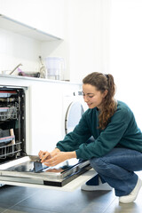 young woman putting a dishwasher in her house after a meal. Woman doing housework.