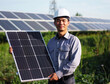 © Edgar Martirosyan - man in helmet holding solar panel on background of photovoltaic park,