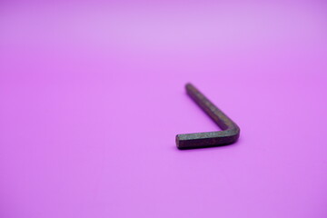 Allen key isolated purple background. a black L key.