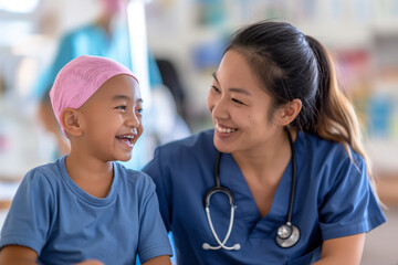 A compassionate nurse in a blue gown smiles at a sick girl with cancer, who is wearing a pink scarf on her head. They share a moment of joy in a hospital setting, highlighting the care and support.