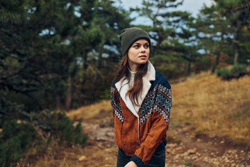 A stylish young woman in a hat and jacket exploring the serene beauty of the forest wilderness