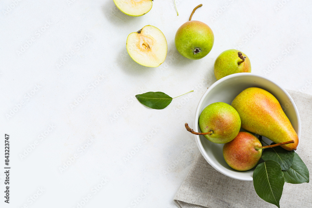 Bowl with ripe pears on white table