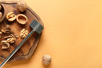 Wooden board of tasty walnuts on beige background