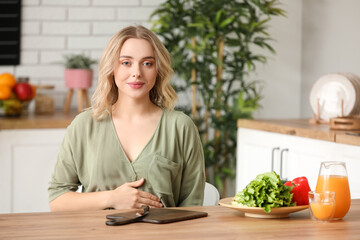 Poster - Young pregnant woman at table in kitchen